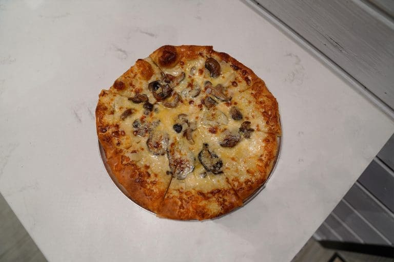 mushroom pizza with white sauce and mushrooms on a white counter in savory neighborhood grill in sandpoint idaho